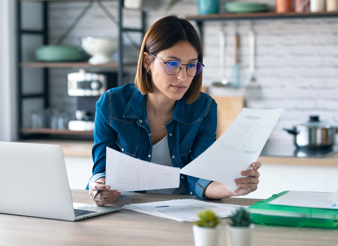 Request Certificate - Woman Working from her Kitchen Table Gathering Insurance Documents