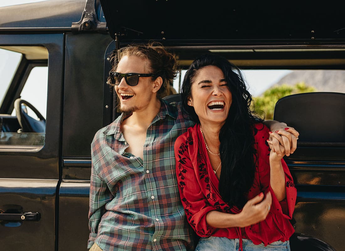 Insurance Solutions - Closeup View of a Joyful Young Couple Having Fun Standing Outside a Black Van During a Summer Road Trip