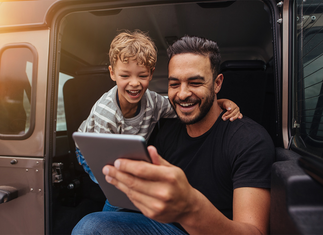 Video Library - Closeup Portrait of a Cheerful Father and Son Watching Videos on a Tablet While Sitting in the Rear of a Van